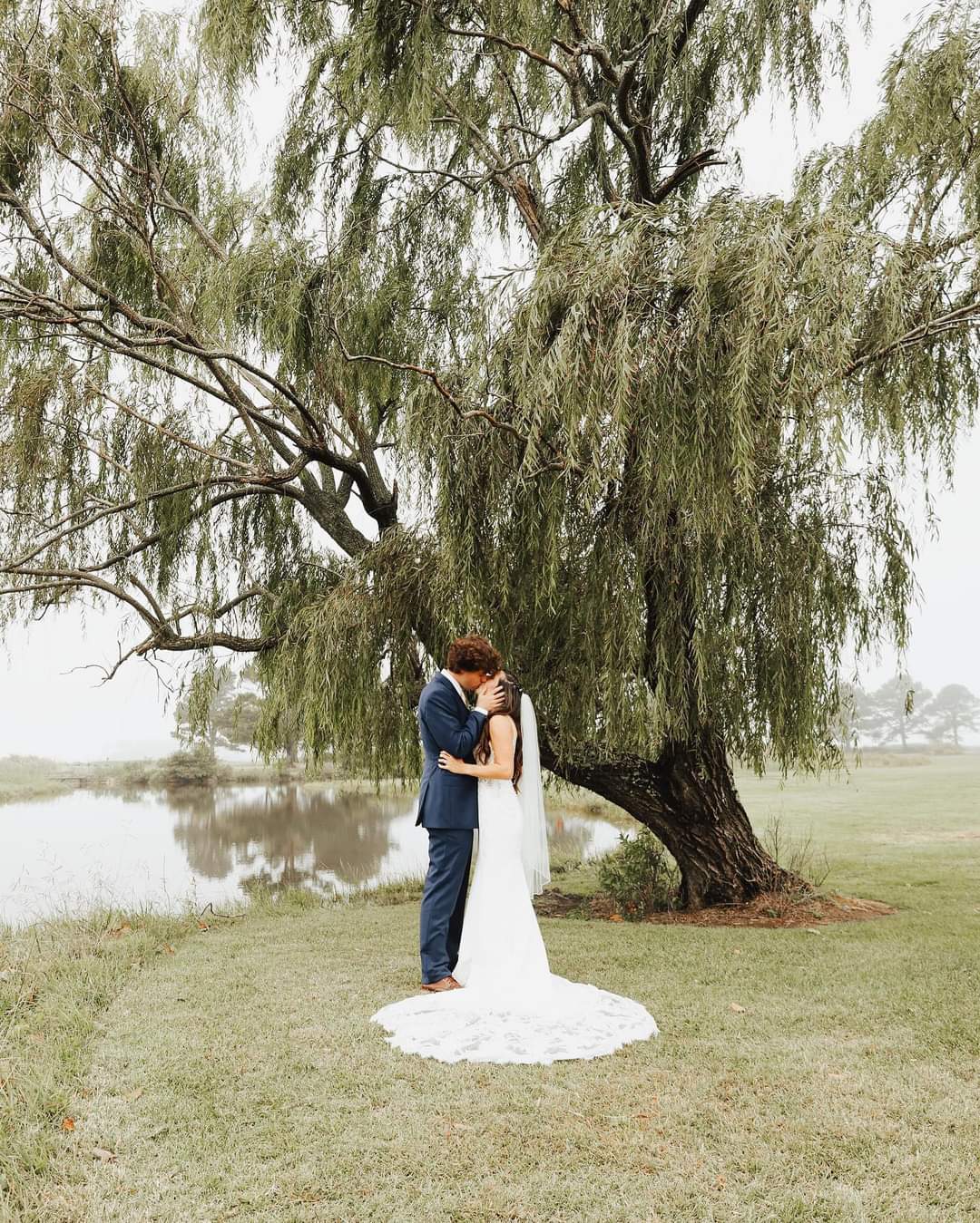 Bride and groom kissing under a weeping willow tree